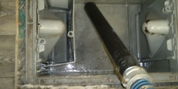 Cleaning a dirty air conditioning drain pan with a hose.