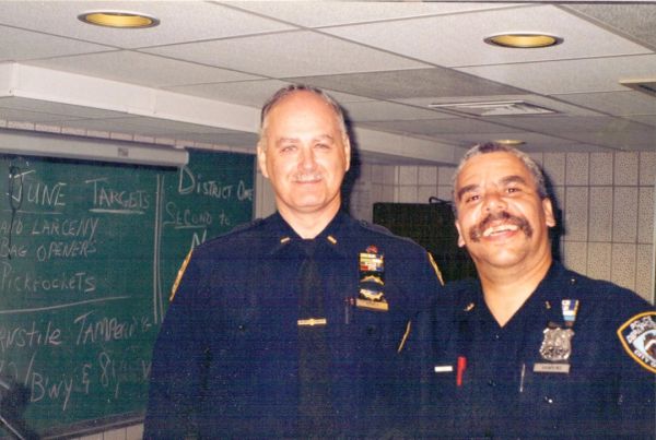Two police officers smiling indoors.