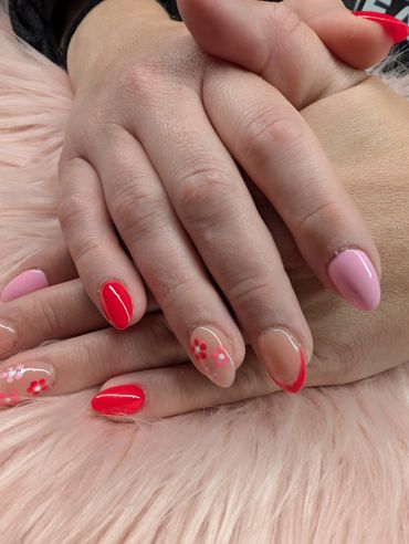 Hands with pink and red manicured nails featuring floral and French tip designs.
