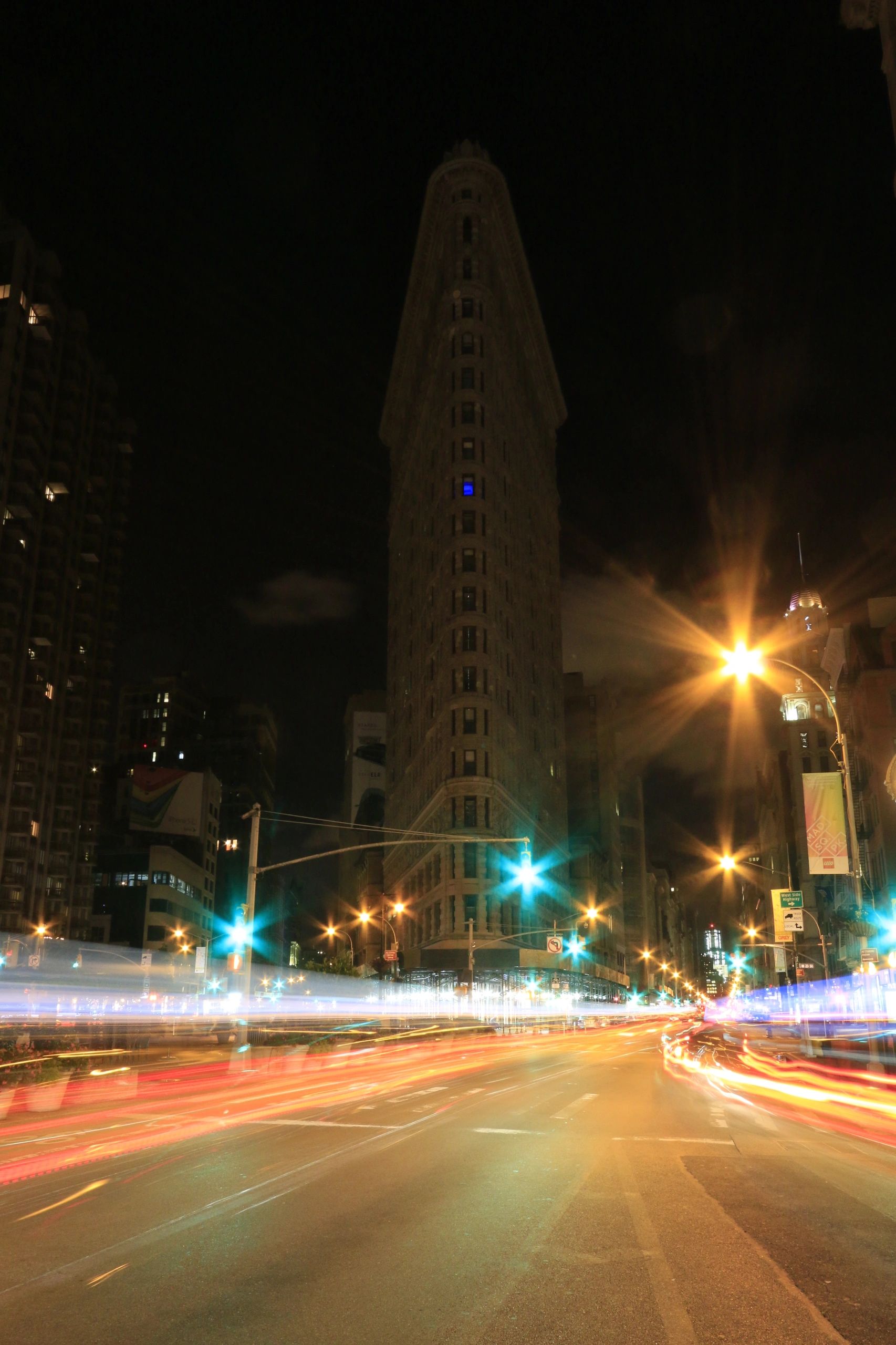 Night view of the Flatiron Building with light trails from cars on the street.