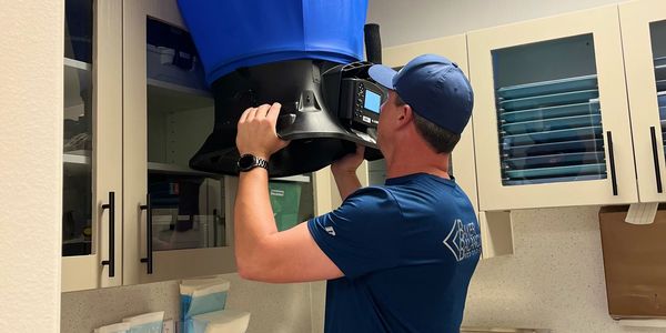 A Test and Balance Technician using a flow hood to read the CFM from a HVAC grille.