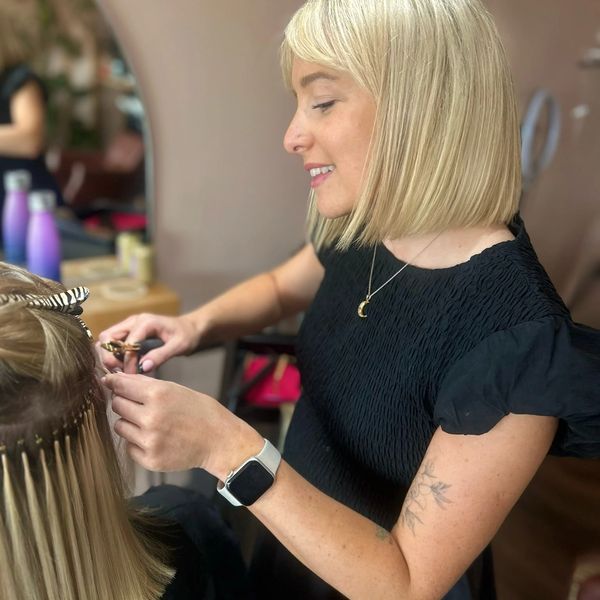 Woman styling hair, smiling.