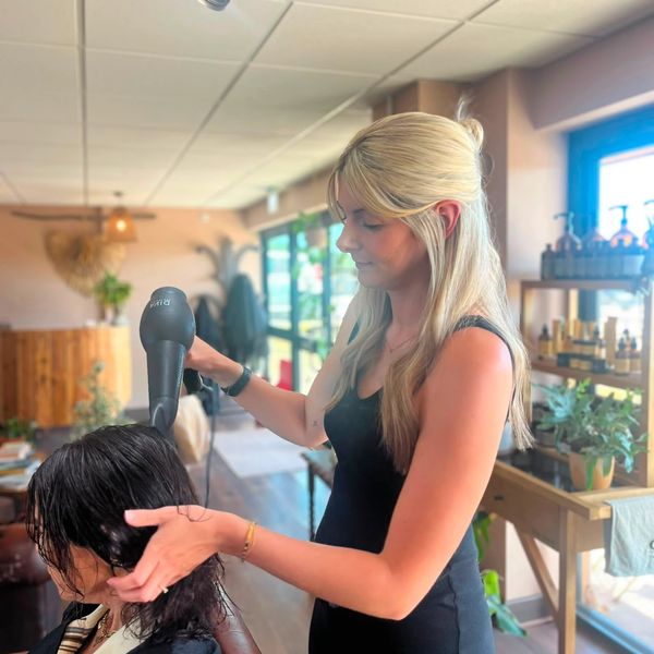 Woman blow-drying another woman's hair in a salon.