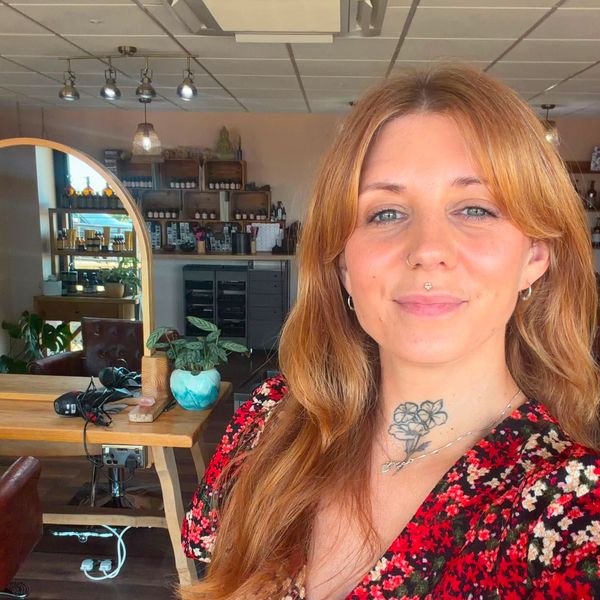 Smiling woman with tattoo in cozy room with plants and mirror.