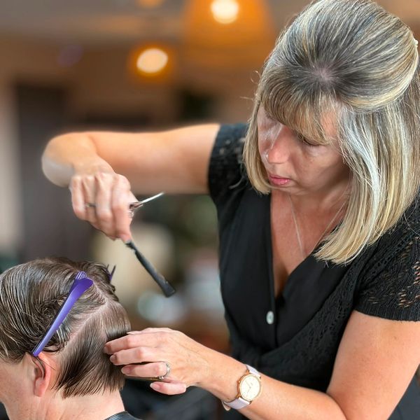 Woman cutting a man's hair in a salon.