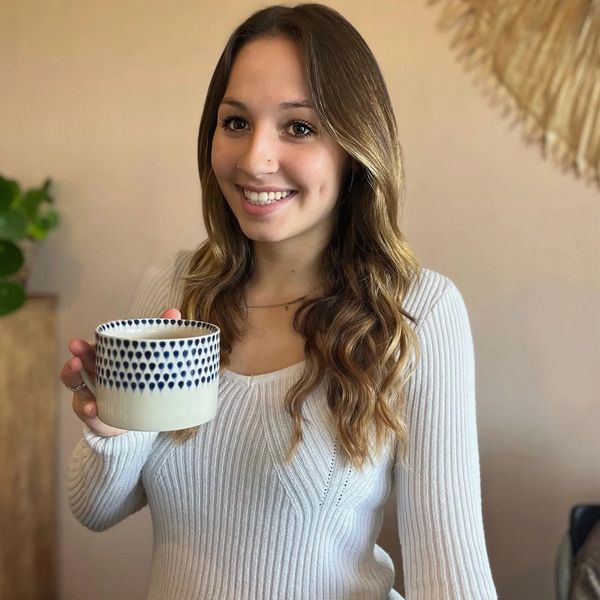 Woman smiling while holding a patterned mug.