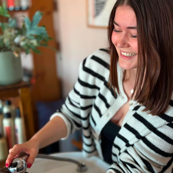 Smiling woman washing hands at a sink.