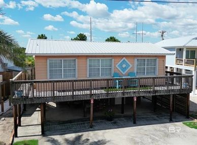 Elevated beach house with wooden deck and pastel peach siding.