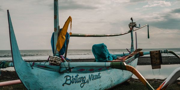 Traditional boat named Bintang Namat on a beach with a cloudy sky.