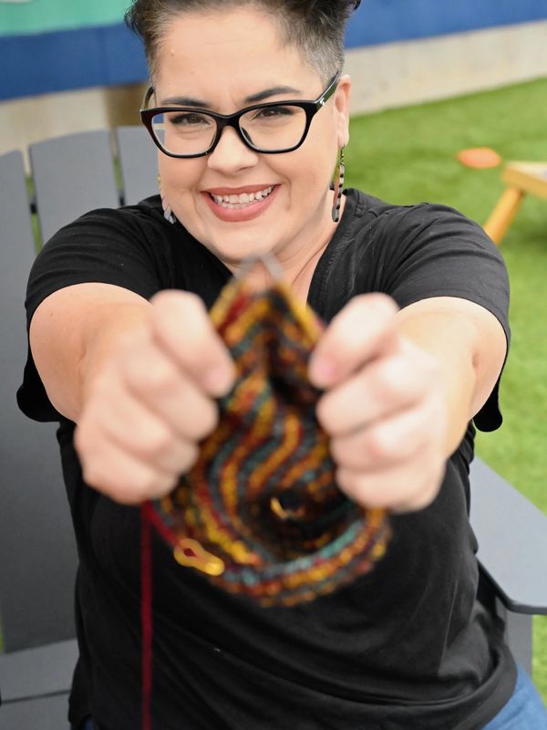 Woman smiling and holding colorful yarn knitting.