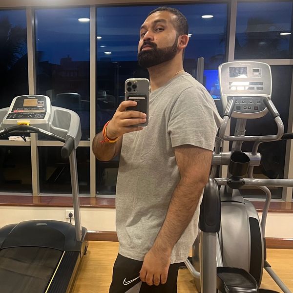 Man taking a gym selfie with exercise equipment in the background.