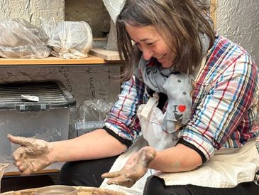 Woman happily working with clay in a pottery studio.