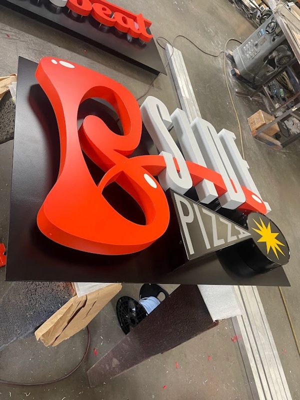 3D signage for a pizza place with bold red and white letters on a black background.