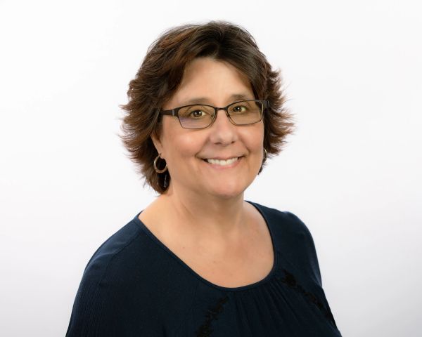 Smiling woman with glasses and short hair.