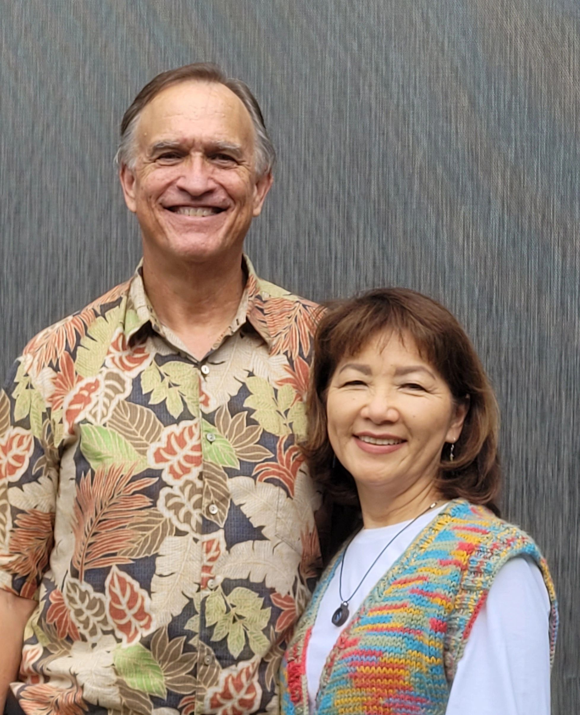 Smiling couple posing together against a plain backdrop.
