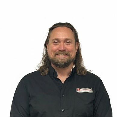 Smiling man with long hair and beard in black shirt.