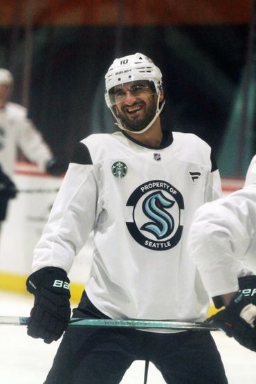 Smiling hockey player in white Seattle jersey during practice.