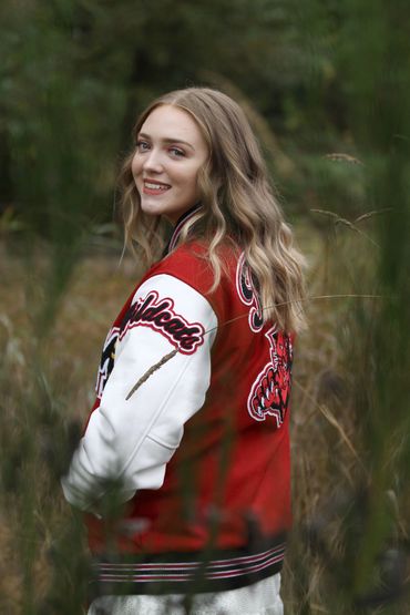 Young woman in a red and white Wildcats jacket smiles outdoors.