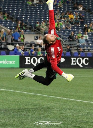 Soccer goalkeeper in mid-air making a save during a match.