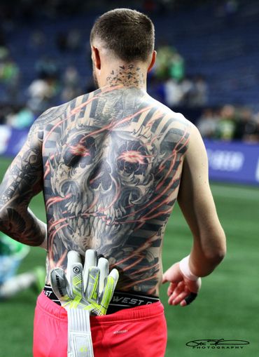 Athlete with a large skull tattoo on his back and gloves tucked into his waistband.