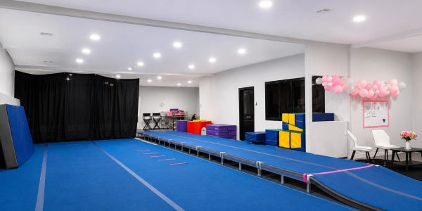 Indoor gymnastics or cheerleading training area with blue mats.