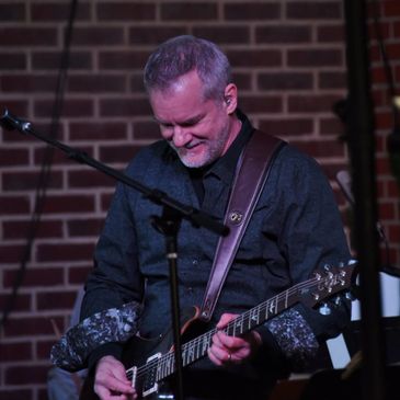 Man playing electric guitar on stage.