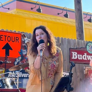 Woman singing on stage with colorful background.