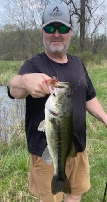 Man holding a large fish he caught near a water body.