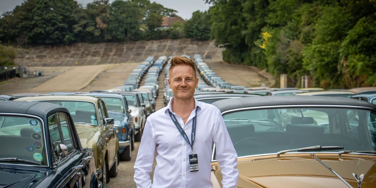 A man standing in front of a line of classic cars.