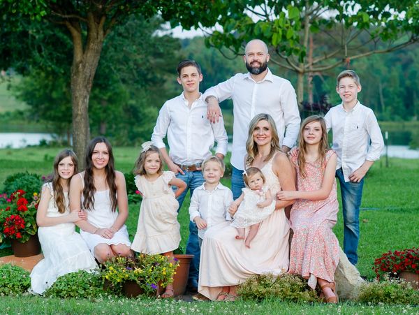 Large family portrait outdoors in a garden.
