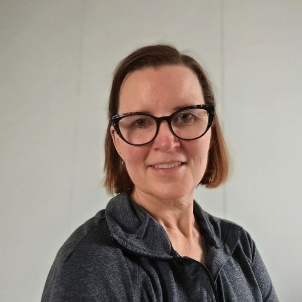 Woman with glasses smiling at the camera.