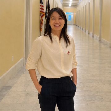 Woman smiling in a hallway with flags.