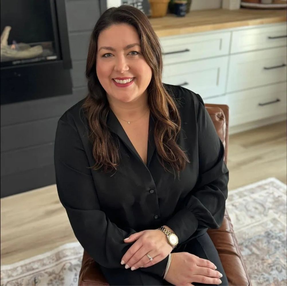 Smiling woman with long hair in a black shirt sitting indoors. Realtor in Knoxville TN