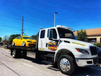 tow truck towing a yellow modified classic car