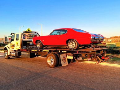 tow truck transporting a red classic car