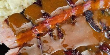 Close-up of a glazed meat slice with mashed potatoes.