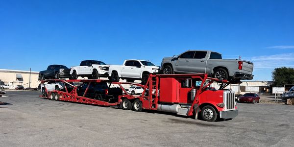 Open auto transport carrier loaded with pickup trucks for nationwide vehicle shipping.