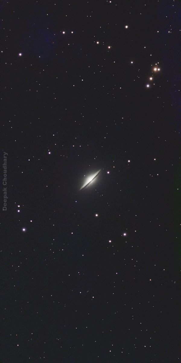 Edge-on galaxy surrounded by stars in deep space.