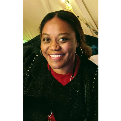 Smiling woman wearing a black sweater with studded details and hoop earrings.