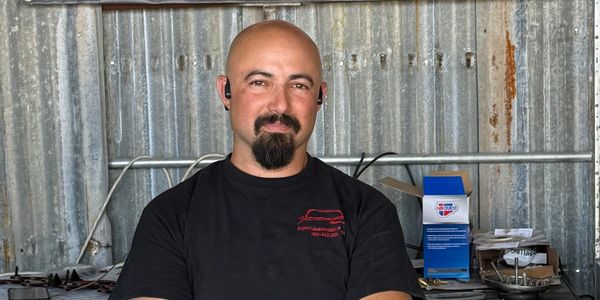Man with a goatee in a black shirt standing in a workshop.