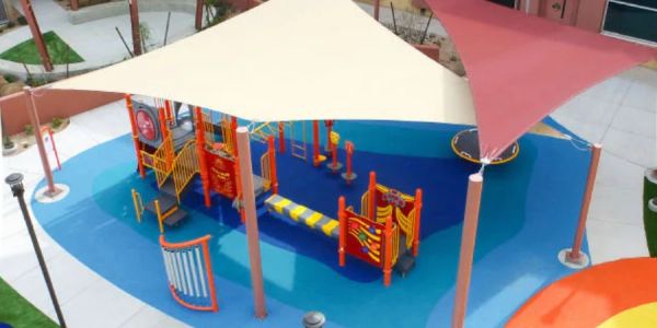 Colorful playground with shade sails and various play structures.
