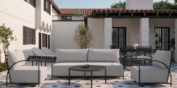 Modern outdoor patio with cushioned seating and tiled flooring under clear skies.