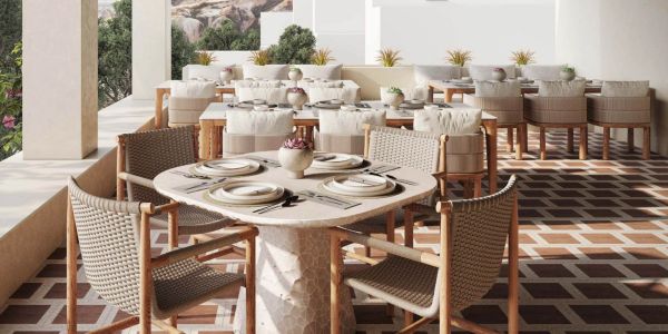 Elegant outdoor dining area with woven chairs and set tables under a covered patio.