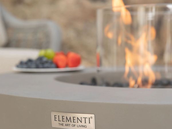 Modern outdoor fire pit with Elementi branding and a cozy flame.