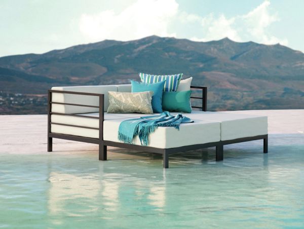 Outdoor daybed with cushions by a pool and mountains in the background.