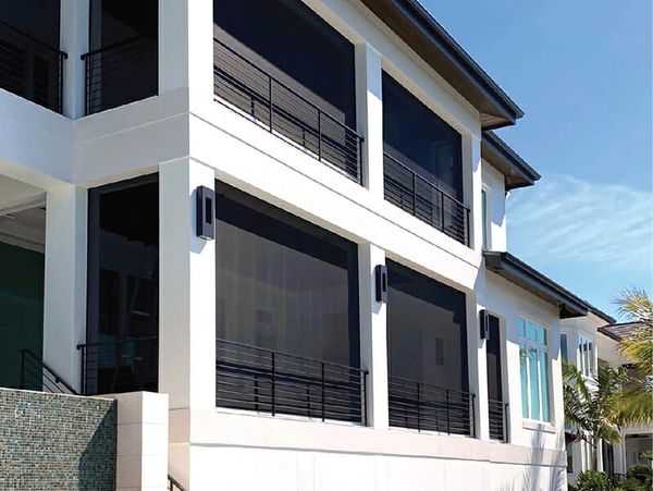 Modern white house with large screened windows and black railings.