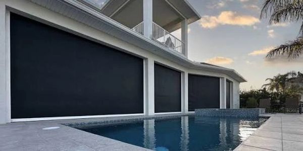 Modern home with large retractable black window shades by the pool.
