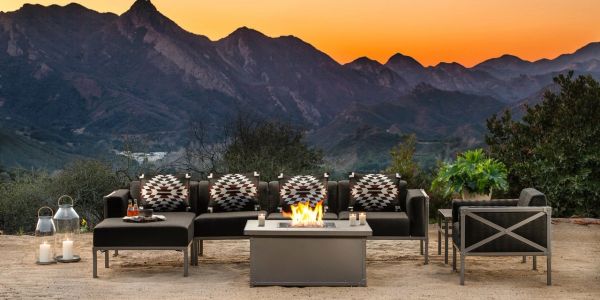 Outdoor seating with a fire pit against a mountain sunset backdrop.