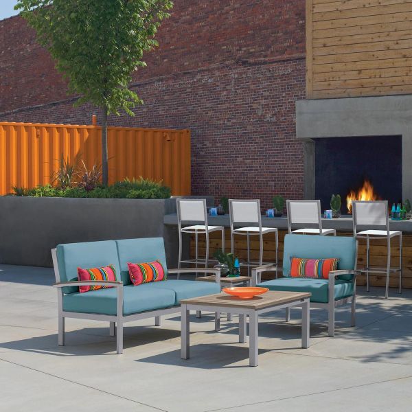 Modern outdoor seating area with blue cushioned chairs and a fireplace.