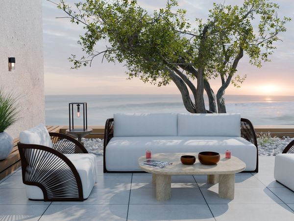Modern outdoor seating area with ocean view and sunset.